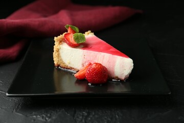 Piece of tasty cheesecake with strawberries, sauce and mint on black table, closeup