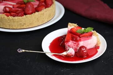 Delicious cheesecake with strawberries, sauce and mint on black table, closeup