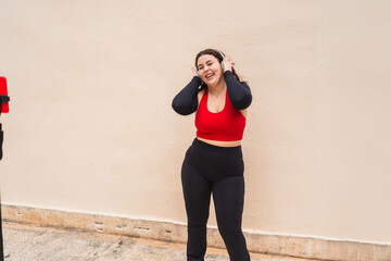 Influencer wearing sportswear listening to music with headphones while recording a fitness video tutorial