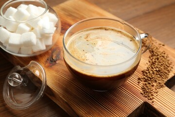Tasty coffee in cup and sugar cubes on wooden table, closeup