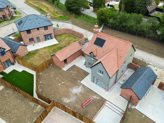 Aerial view of a newly completed, detached home and garage seen. on a housing development site in Britain. Seen together with other larger homes.