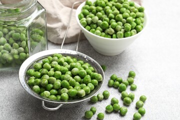 Fresh green peas and pickling jar on light grey table, closeup