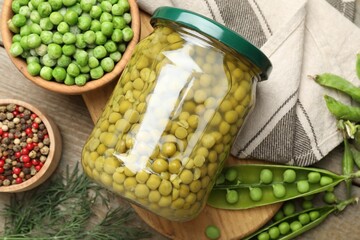 Pickled peas in jar, spices, dill and pods on wooden table, flat lay