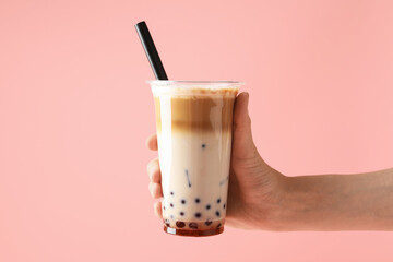 Woman with tasty milk bubble tea on pink background, closeup
