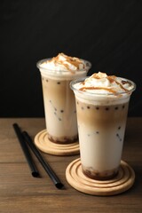 Tasty milk bubble tea in plastic cups on wooden table