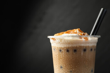 Tasty milk bubble tea in plastic cup on black background, closeup. Space for text