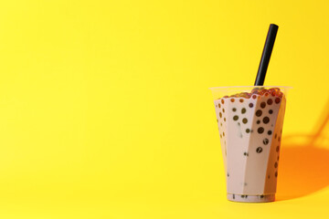 Tasty milk bubble tea in glass on yellow background, space for text