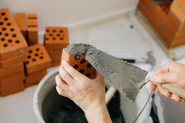 A young man makes brickwork on the chimney of a fireplace.