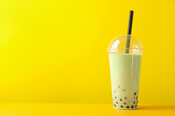 Tasty milk bubble tea in plastic cup on yellow background. Space for text