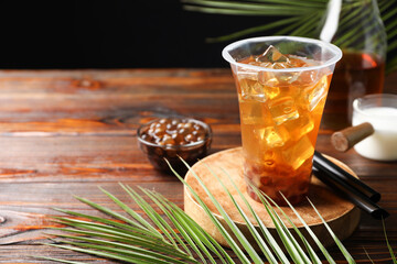 Tasty iced bubble tea and ingredients on wooden table. Space for text