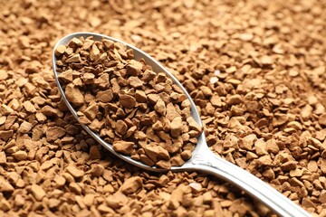 Spoon with aromatic instant coffee as background, closeup