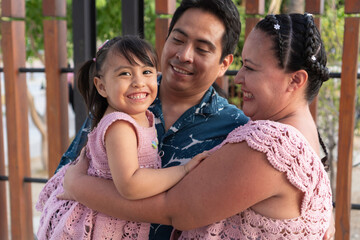 Happy hispanic family embracing and smiling together outdoors