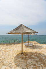 Sonnenschirm und Sonnenliegen an einer typischen Badestelle am Strand von Porec an der kroatischen...
