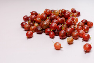 A handful of fresh gooseberries in drops of water, close-up, top view, on a light background