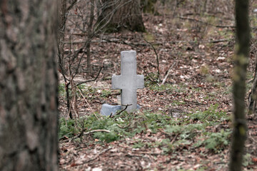 A small grave with a stone cross in the forest. Pet cemetery