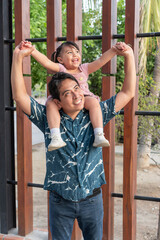 Obraz premium Happy hispanic father carrying daughter on shoulders, enjoying family time outdoors