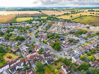 Aerial view of a rural village in the heart of the Essex, UK countryside. In the distance, a new housing development can be seen in progress.