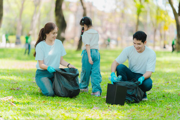 Asian family on summer vacation, parents teaching children to pick up plastic bottles and trash in...