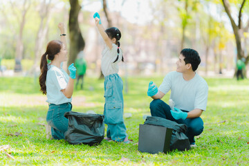 Asian family on summer vacation, parents teaching children to pick up plastic bottles and trash in...