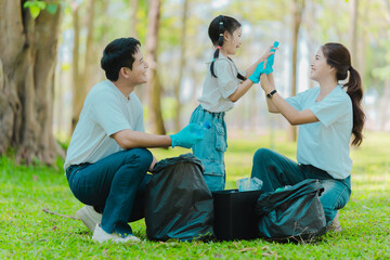 Asian family on summer vacation, parents teaching children to pick up plastic bottles and trash in...