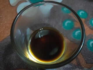Close-up overhead shot of dark liquid residue in a clear glass cup.