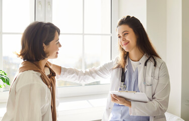 Doctor or nurse assisting a patient during a consultation in a hospital office. Delivering...