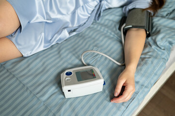 Fototapeta premium Close-up of digital blood pressure monitor and female hand during health measurement, medical technology and wellness concept