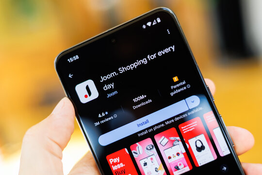 Phone in hand displaying Joom app on Google Play Store