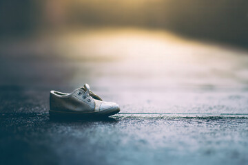 Old worn-out sneaker abandoned on wet asphalt after rain, lonely footwear, outdoor, urban scene, abandoned shoe, reflection, puddle, rainy day, sidewalk