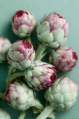 Obraz premium Fresh artichokes showing vibrant green and pink hues on a teal background