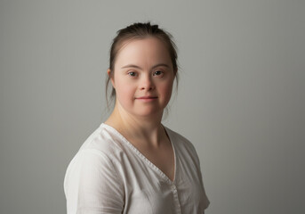 Young woman with down syndrome looking confidently at camera, natural expression, soft lighting, emphasizing beauty, strength, and authenticity in a neutral background