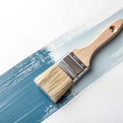 A paintbrush applies a textured stroke of blue paint across a white surface creating a gradient of color