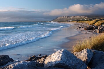 Coastal scene captures the serene beauty of a sandy beach with gentle waves washing ashore under a