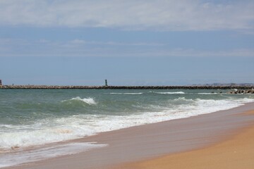 Ocean Shoreline with Receding Wave and Distant Pier