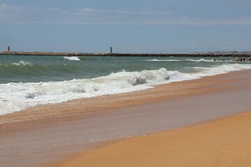 Ocean Shoreline with Receding Wave and Distant Pier