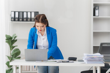 Portrait of beautiful businesswoman talking on the phone and working on laptop while sitting in...