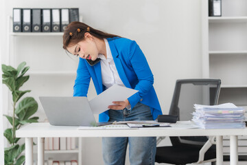 Portrait of beautiful businesswoman talking on the phone and working on laptop while sitting in...