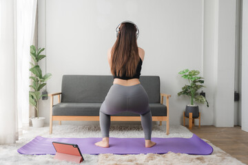 Online Yoga Class: A woman performs a side bend yoga pose on a purple mat at home, following...