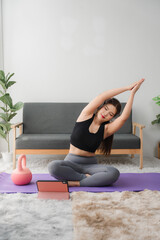 Online Yoga Class: A woman performs a side bend yoga pose on a purple mat at home, following...
