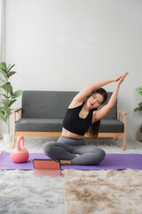Online Yoga Class: A woman performs a side bend yoga pose on a purple mat at home, following...