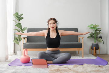 Online Yoga Class: A woman performs a side bend yoga pose on a purple mat at home, following...