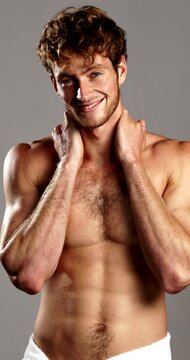 Confident, skincare and face of man with towel in studio for wellness, cleaning or hygiene routine. Gray background, muscular body and portrait of topless person for shower, grooming and dermatology
