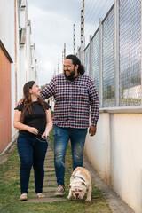 Park romance: couple and bulldog under sunlight. A joyful couple shares a sunny park moment with...