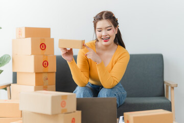 Young business woman working online e-commerce shopping at her shop. Young asia woman seller prepare parcel box of product for deliver to customer. Online selling. E-commerce.