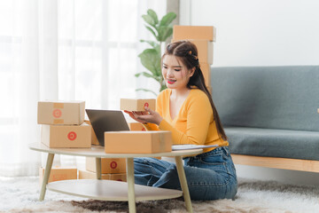 Young business woman working online e-commerce shopping at her shop. Young asia woman seller...