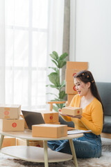 Young business woman working online e-commerce shopping at her shop. Young asia woman seller prepare parcel box of product for deliver to customer. Online selling. E-commerce.