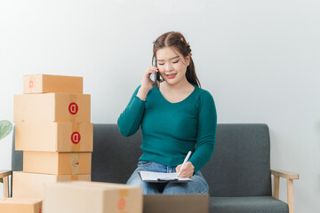 Young business woman working online e-commerce shopping at her shop. Young asia woman seller prepare parcel box of product for deliver to customer. Online selling. E-commerce.