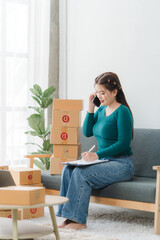 Young business woman working online e-commerce shopping at her shop. Young asia woman seller prepare parcel box of product for deliver to customer. Online selling. E-commerce.