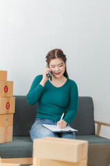Young business woman working online e-commerce shopping at her shop. Young asia woman seller prepare parcel box of product for deliver to customer. Online selling. E-commerce.