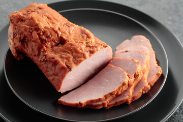 Smoked ham on a black plate.